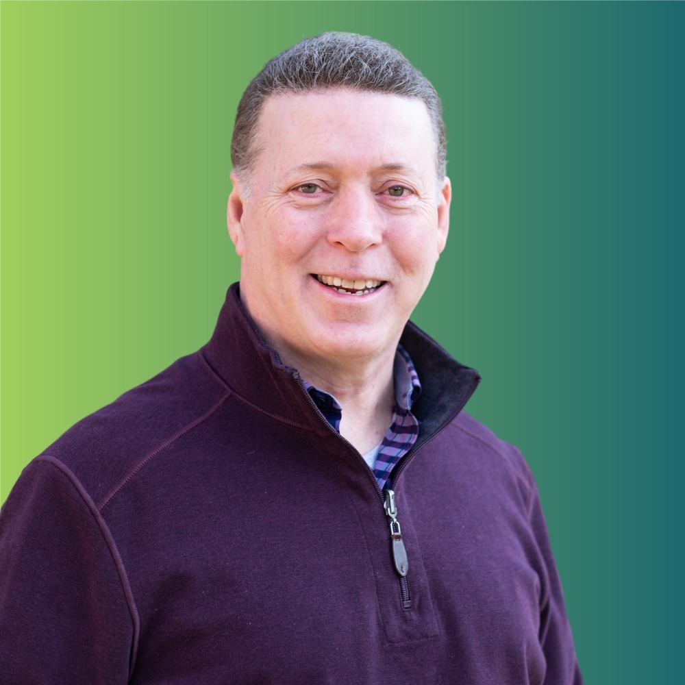 Michael Lamb headshot white man with short hair wearing a purple half zip long sleeve shirt
 