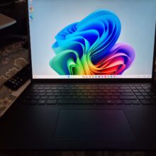 photo of a bllack laptop with a multicolor flower as the screensaver